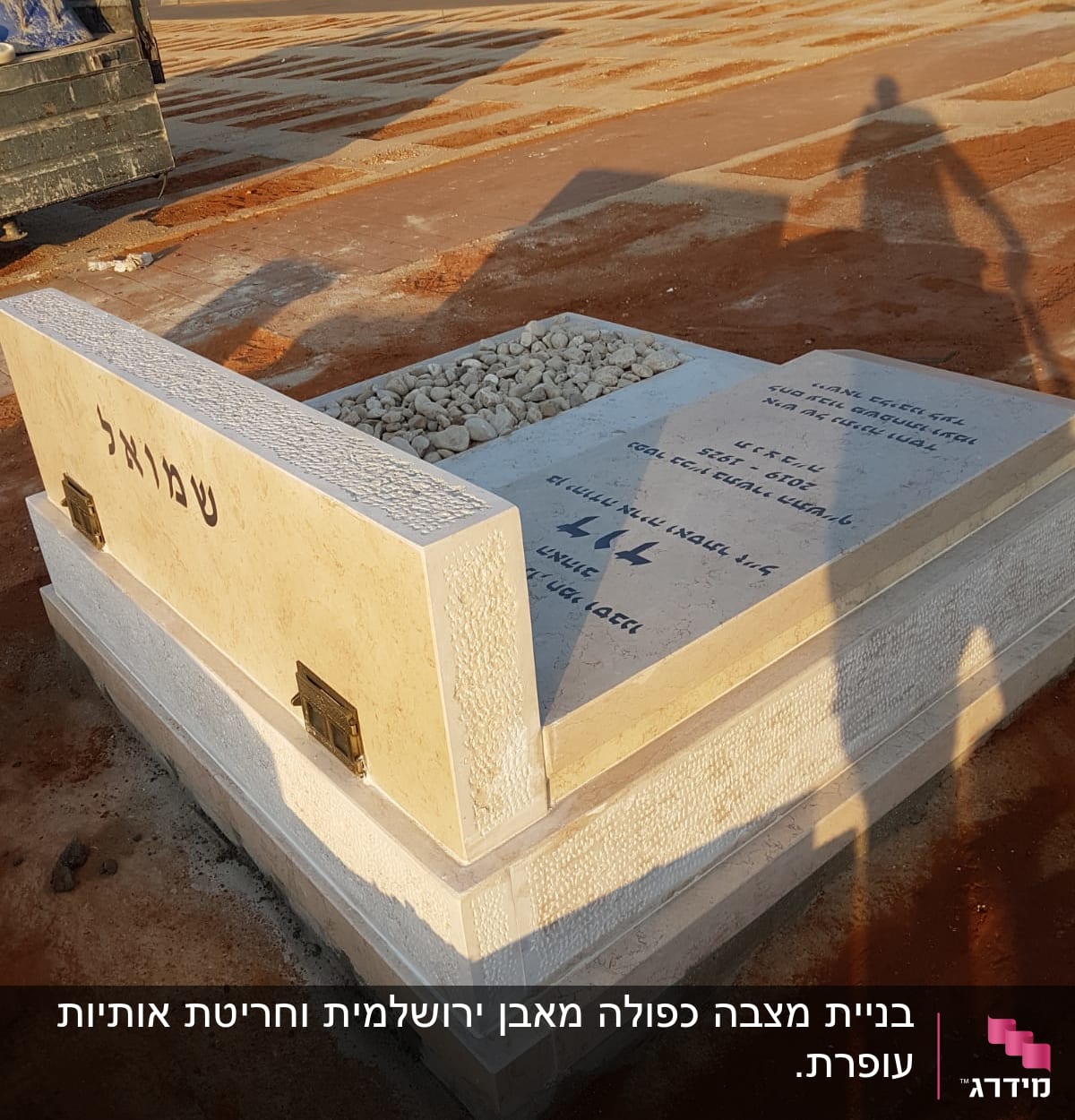 מצבה עם כיתוב בעברית ואבנים קטנות